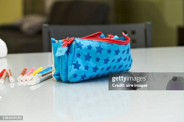 view of blue pencil case with stars on dining table at home, distance education due to covid-19. markers next to school pencil case. - etui stockfoto's en -beelden