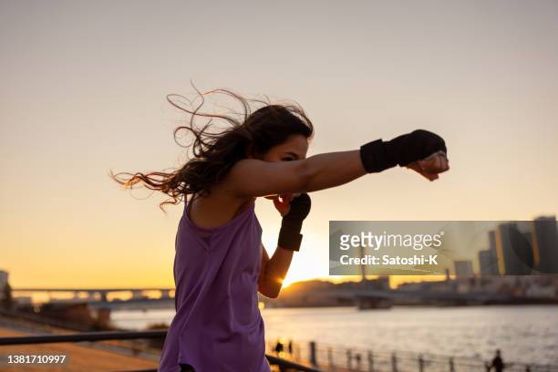 entrenamiento de boxcer hembra joven en el parque público bayside a la hora del atardecer - golpe directo - boxing fotografías e imágenes de stock