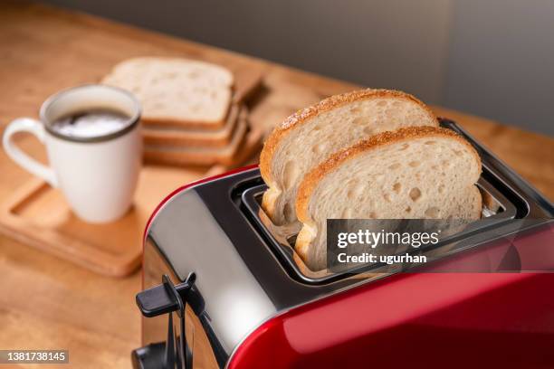 on the kitchen table is a red toaster and a cup of coffee. - toaster stockfoto's en -beelden