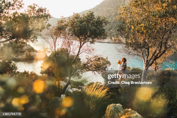 young happy couple kissing with amazing sea and mountain coastline view. romantic feelings and love - mediterranean sea stock pictures, royalty-free photos & images
