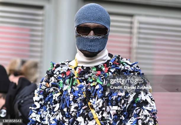 Guest is seen wearing a ripped clothing sweater, GCDS yellow bag and a blue balaclava outside the Valentino show during Paris Fashion Week A/W 2022...