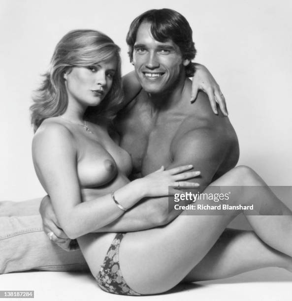Actor and bodybuilder Arnold Schwarzenegger poses with a topless model, circa 1982.