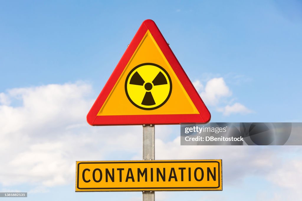 Danger traffic sign with the nuclear symbol and sign that says: 'CONTAMINATION', with the sky in the background. Concept of war, Ukraine, Russia and war conflict. Concept of energy and chemical weapon,.