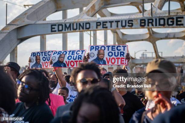 People march across the Edmund Pettus Bridge with placards bearing the image of the late U.S. Rep. John Lewis, for whom the most recent voting rights...