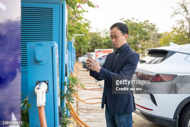 asian man scanning payment on mobile phone to charge car - animals charging stock pictures, royalty-free photos & images