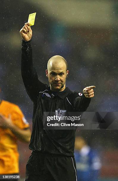 Referee Anthony Taylor shows a yellow card during the Barclays Premier League match between Wigan Athletic and Everton at DW Stadium on February 4,...