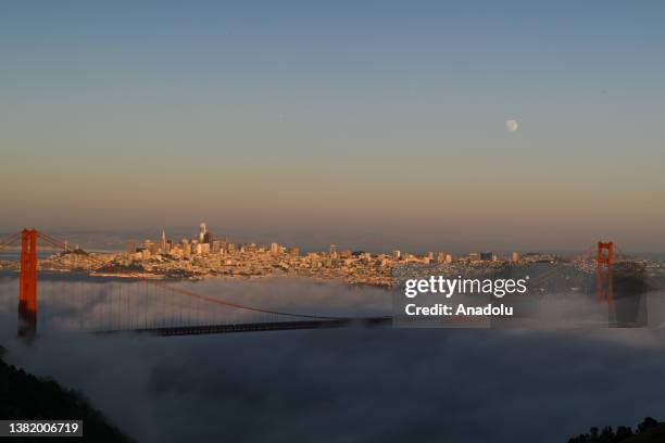 Full Moon rises over San Francisco's Golden Gate Bridge during foggy day as seen from Marin Headlands of Sausalito in California, United States on...