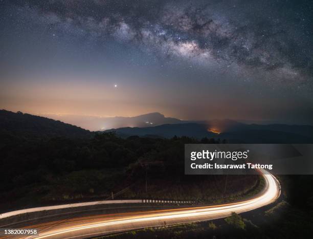 milky way galaxy with lighting on the road at doi inthanon chiang mai, thailand.long exposure photograph.with grain - kilometer fotografías e imágenes de stock