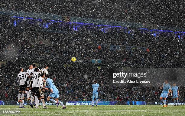 Aleksandar Kolarov of Manchester City fires in a free kick as snow falls during the Barclays Premier League match between Manchester City and Fulham...