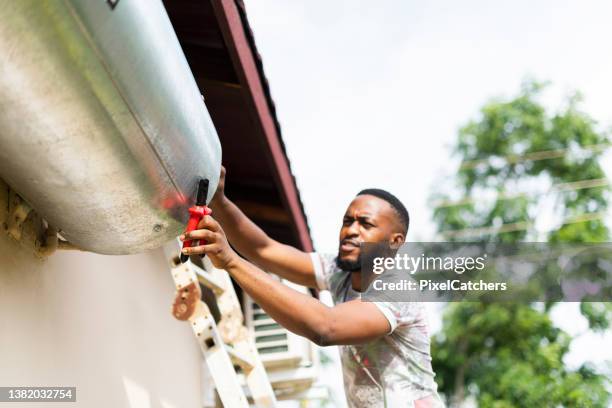 close up man using tools trying to fix hot water geyser - geiser stockfoto's en -beelden