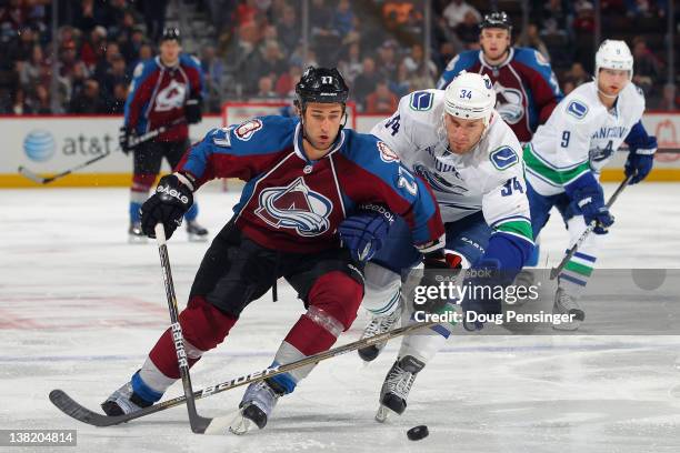 Kyle Quincey of the Colorado Avalanche controls the puck as Byron Bitz of the Vancouver Canucks pursues at the Pepsi Center on February 4, 2012 in...