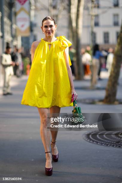 Guest wears a yellow halter-neck / knot shoulder / sleeveless puffy short dress, a green shiny leather nailed / studded handbag from Valentino,...