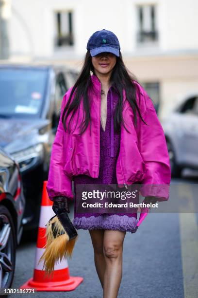 Guest wears a black ribbed velvet cap from New Era, a purple lace flower print pattern V-neck short dress with pale purple feather borders, a purple...