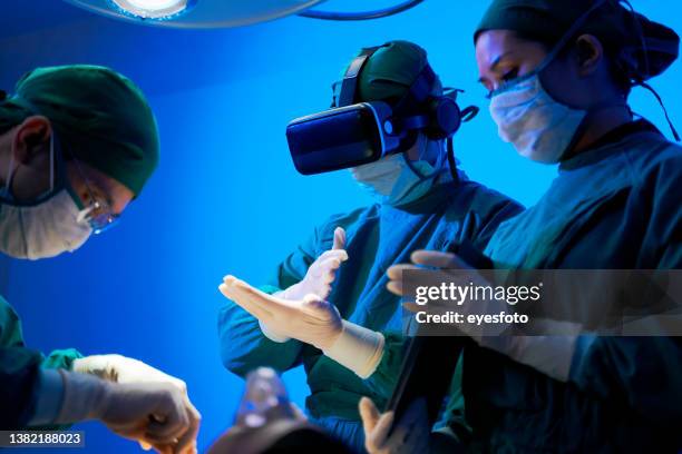 医師は手術室で患者に手術を受けています。バーチャルリアリティメガネを使用しています。 - operating room ストックフォトと画像