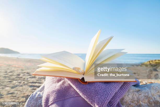 still life of an open book at beach - hardcover book stock pictures, royalty-free photos & images