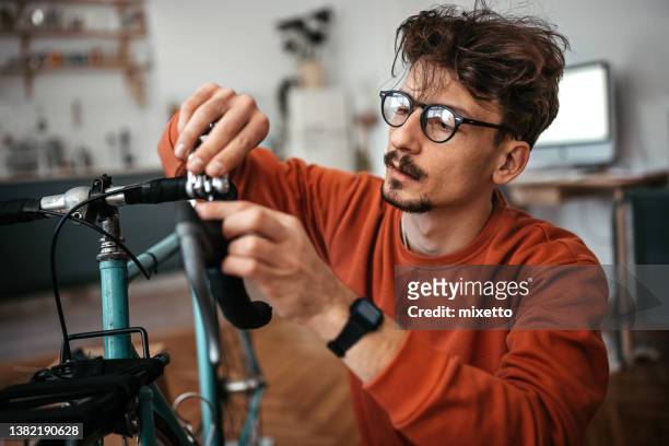 close-up of man adjusting bicycle handlebar at home - bike handle stock pictures, royalty-free photos & images