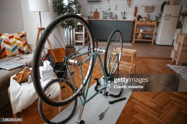 junger mann repariert fahrrad zu hause - fahrrad reparieren stock-fotos und bilder