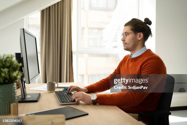 jovem empresário caucasiano trabalhando em computador no escritório - coque masculino - fotografias e filmes do acervo