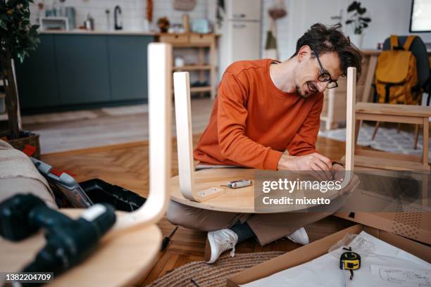 giovane che installa un tavolo di legno con trapano a casa - mobili foto e immagini stock