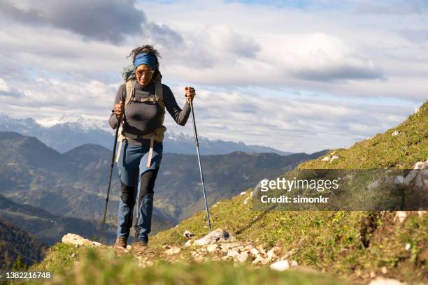 woman hiking on mountain against cloudy sky - grijze broek stockfoto's en -beelden