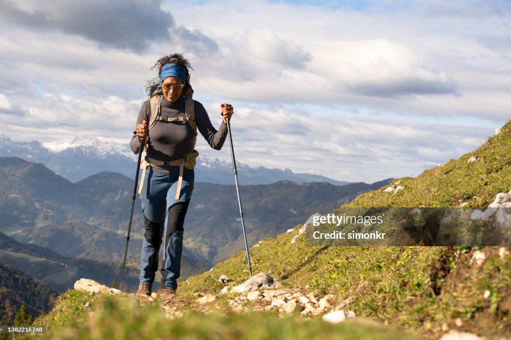Woman hiking on mountain against cloudy sky