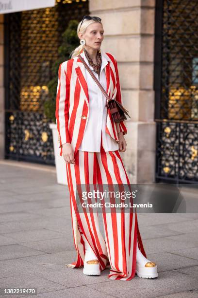 Guest wearing an orange and white striped suit, white shirt, white Schiaparelli shoes and burgundy bag, is seen outside Schiaparelli, during Paris...