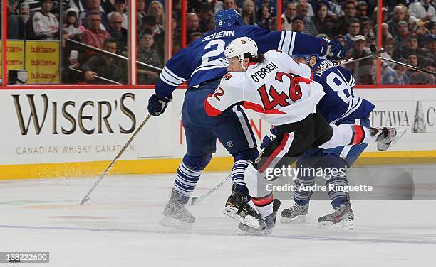 Luke Schenn of the Toronto Maple Leafs body checks Jim O'Brien of the Ottawa Senators off the puck at Scotiabank Place on February 4, 2012 in Ottawa,...