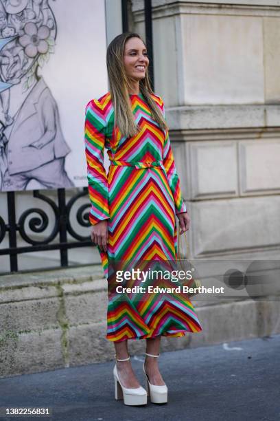 Guest wears a multicolored wavy striped print pattern long sleeves / belted long dress from Valentino, a gold metallic clutch, white shiny varnished...