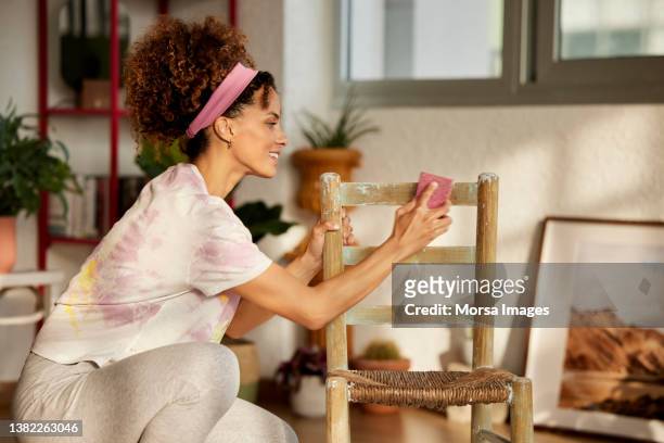 smiling woman polishing chair in living room - restoring chair stock pictures, royalty-free photos & images