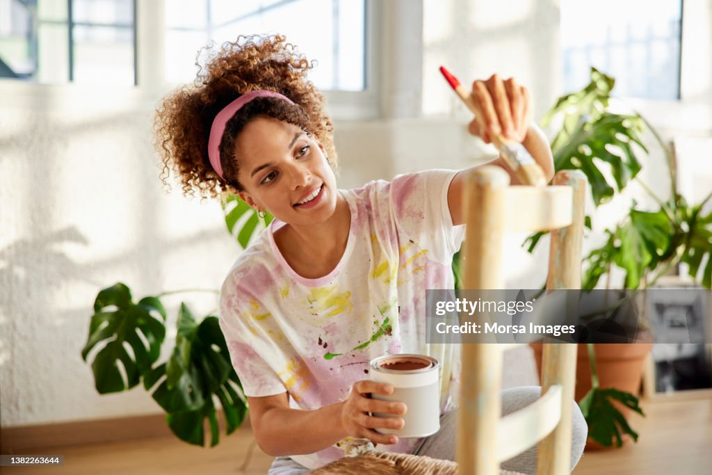 Young Female Painting Chair In Living Room