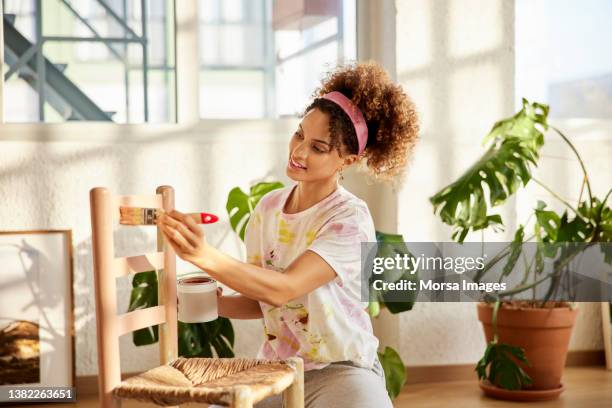 young woman painting chair at home - kunstnijverheid stockfoto's en -beelden