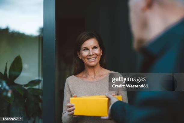 happy woman receiving package from delivery person at doorway - answering door stock pictures, royalty-free photos & images