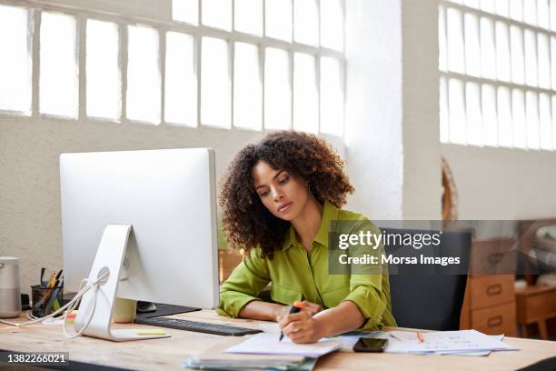 businesswoman writing on document sitting at desk - writer computer stock pictures, royalty-free photos & images