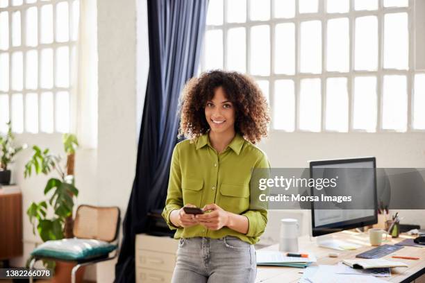 smiling female professional using smart phone - woman business desk front laptop office fotografías e imágenes de stock