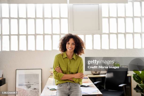 businesswoman with arms crossed at home office - portrait of young woman standing against steps stockfoto's en -beelden