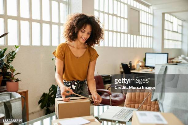 female entrepreneur packing box at home - büromaterial stock-fotos und bilder