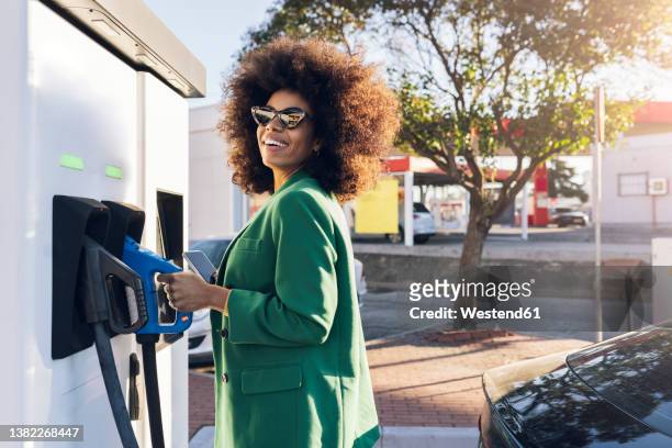 happy businesswoman with fuel pump at gas station - zapfsäule stock-fotos und bilder
