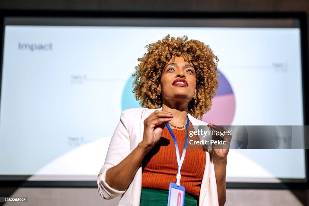 Casualmente vestida hipster mulher segurando um discurso em uma conferência