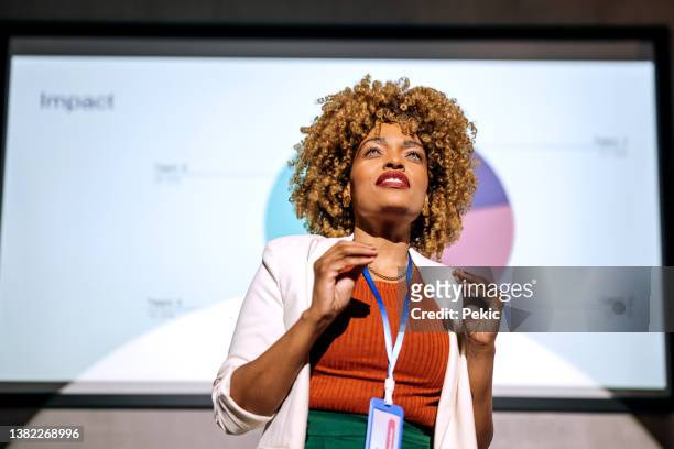 casually clothed hipster woman holding a speech on a conference - presenting imagens e fotografias de stock