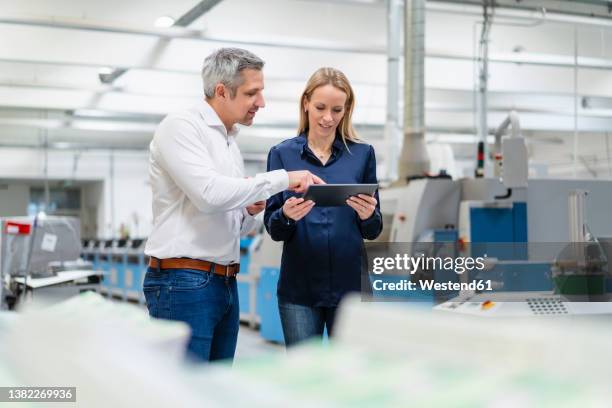 businessman discussing over tablet pc with businesswoman in industry - 40 44 years blond hair mature man factory stock pictures, royalty-free photos & images