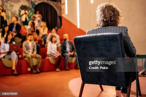 rückansicht des konferenzmoderators, der vor publikum sitzt - women podium stock-fotos und bilder