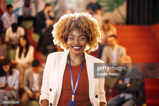 female presenter posing in front of audience in conference hall - award ceremony stock pictures, royalty-free photos & images