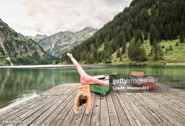 girl doing cartwheel on jetty by lake - flexible work stock-fotos und bilder