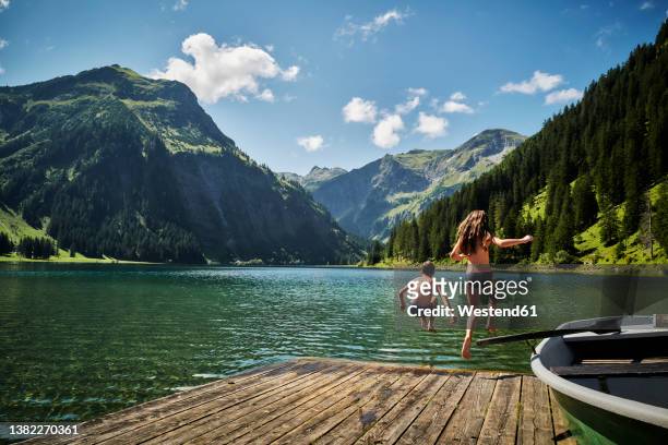 sister and brother jumping into vilsalpsee lake - bergsteiger stockfoto's en -beelden