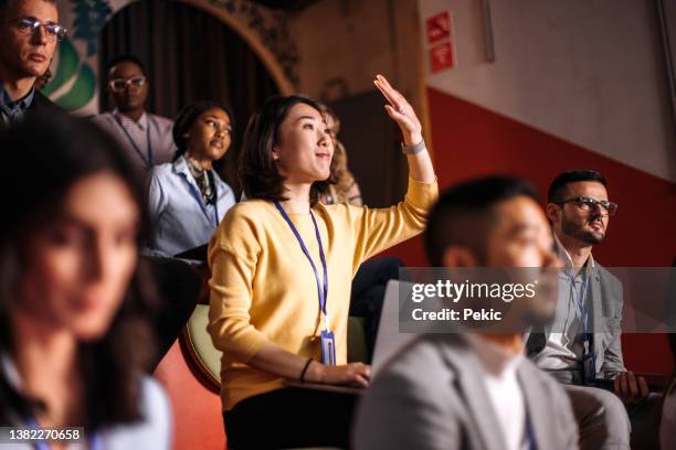 young beautiful woman asking a question during business conference - attending conference stock pictures, royalty-free photos & images