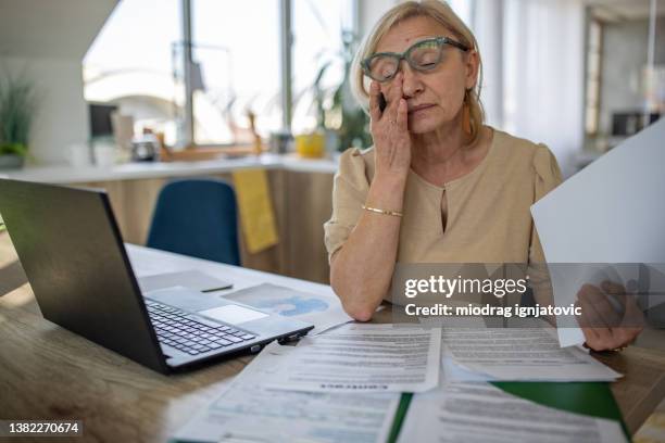 tired mature woman rubbing eyes while telecommuting from home - rubbing eyes stock pictures, royalty-free photos & images