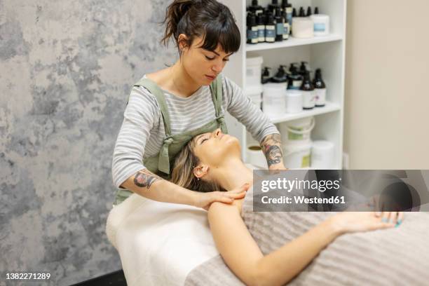 therapist giving massage to woman at aesthetic clinic - エステティシャン ストックフォトと画像