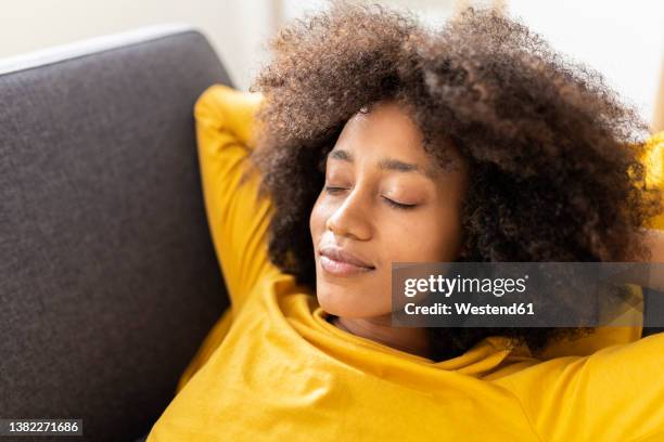 young woman with eyes closed relaxing at home - hands behind head stock pictures, royalty-free photos & images