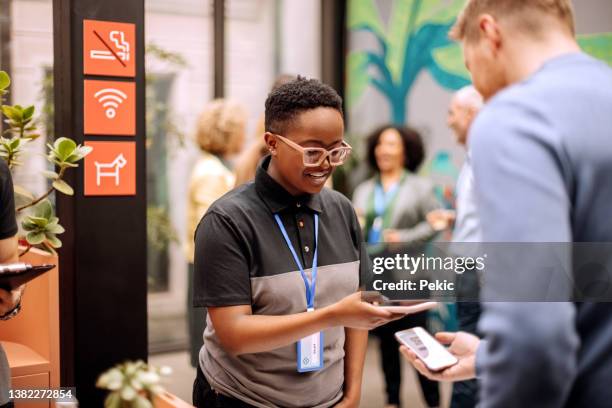 gestionnaires autorisés portant un badge et enregistrant les préposés à l’entrée de la conférence - promoteur photos et images de collection