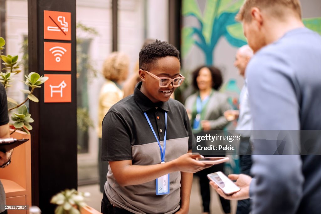 Authorised managers wearing a badge and checking in attendants at the conference entrance